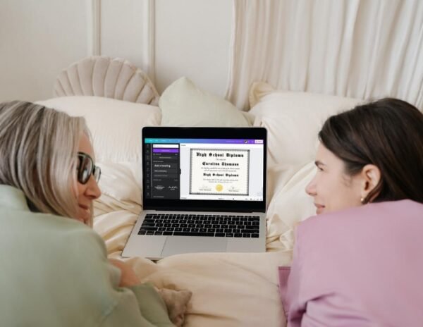 A GED diploma template in PDF format with a gold seal displayed on a laptop on the bed, held by a young woman and her mother