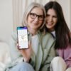 Young Woman and Mother Viewing Equivalency Diploma in Canva on Mobile