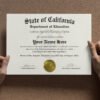 Hands holding a high school diploma with a gold seal.